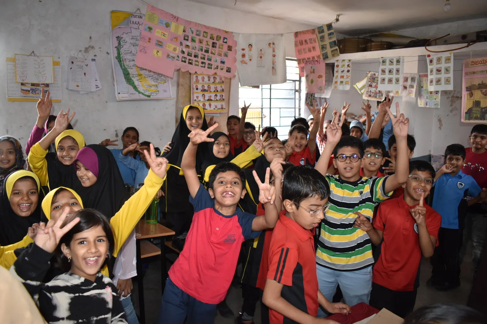 Children raising their hands in a classroom.
