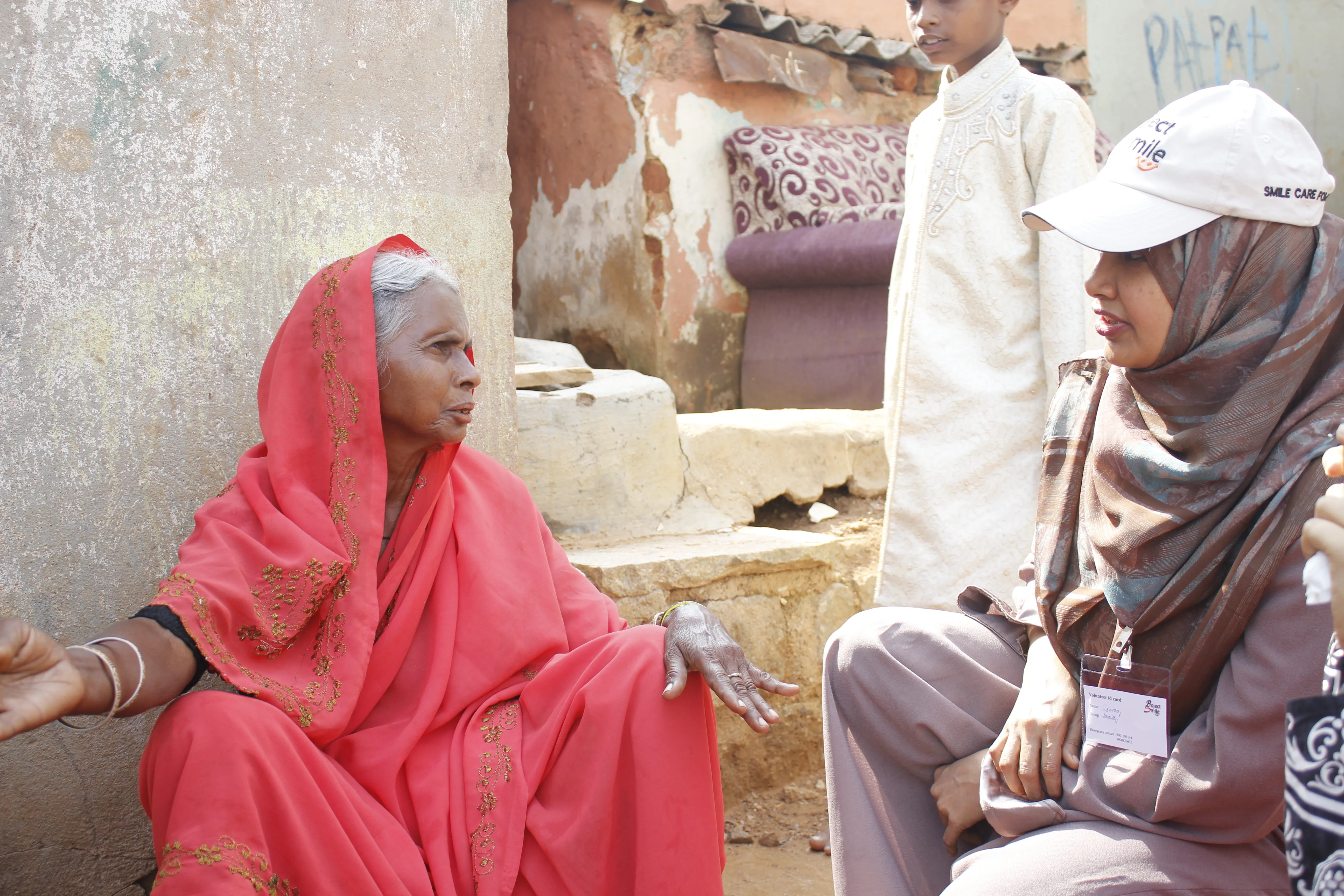 Care team member speaking with a mother outside her home.