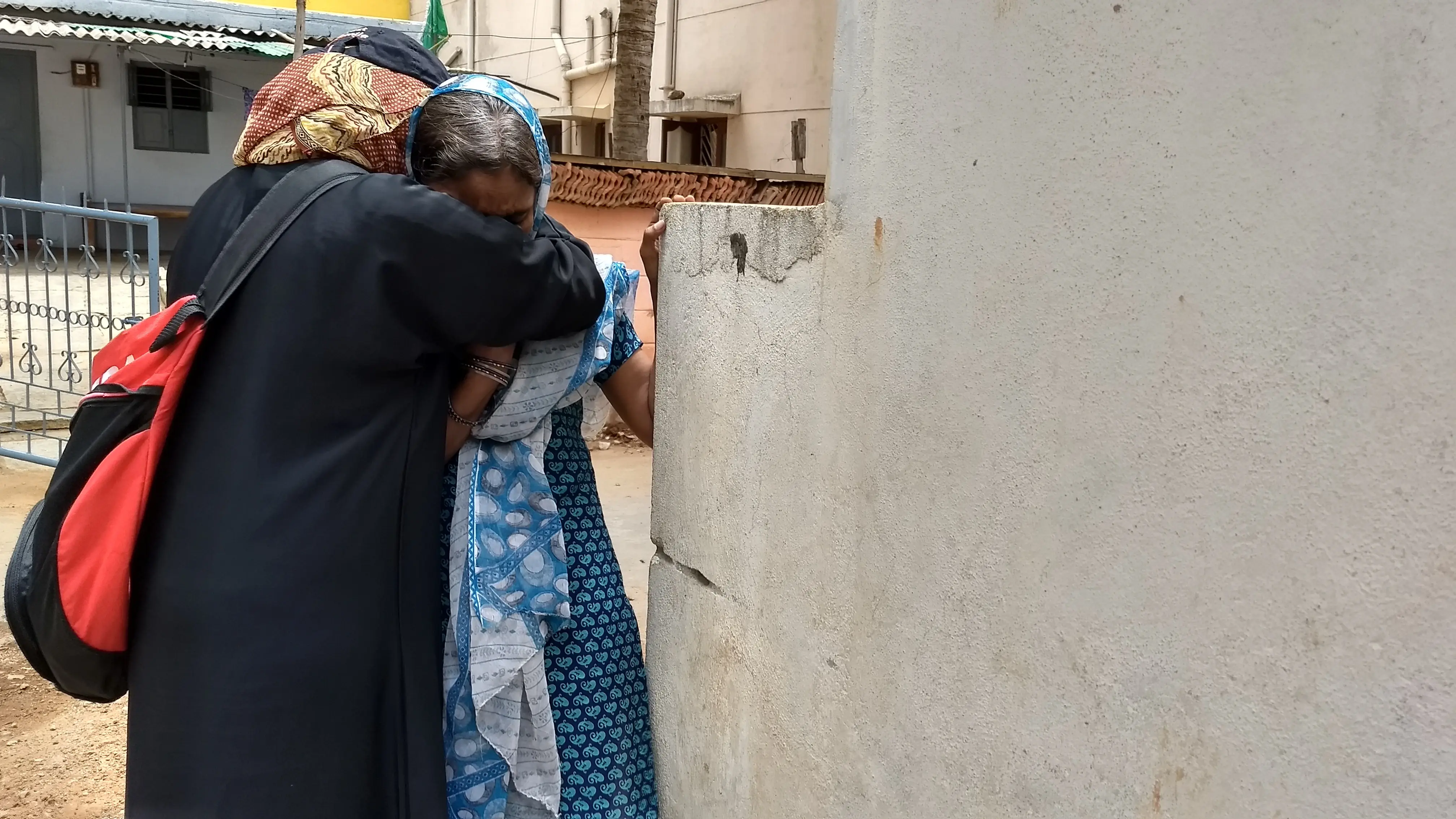Two women embracing outside a home.