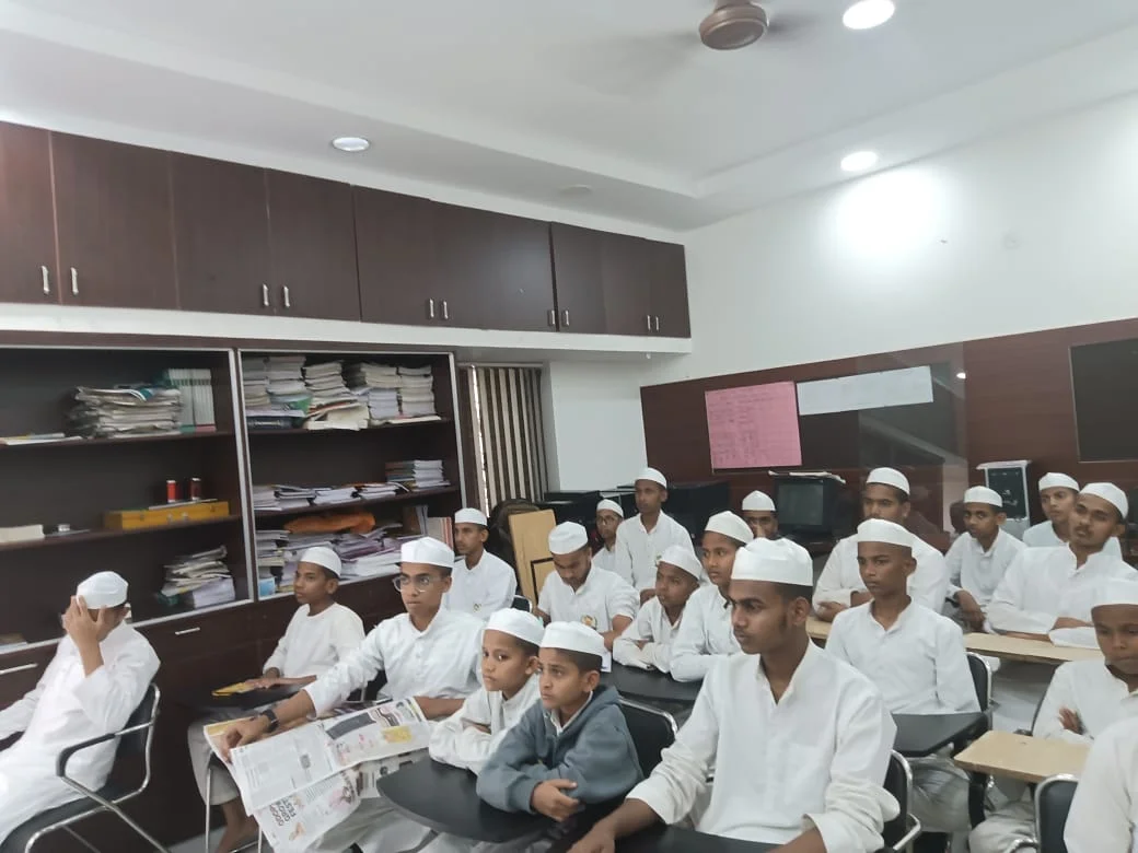 Students seated in a classroom wearing white caps.